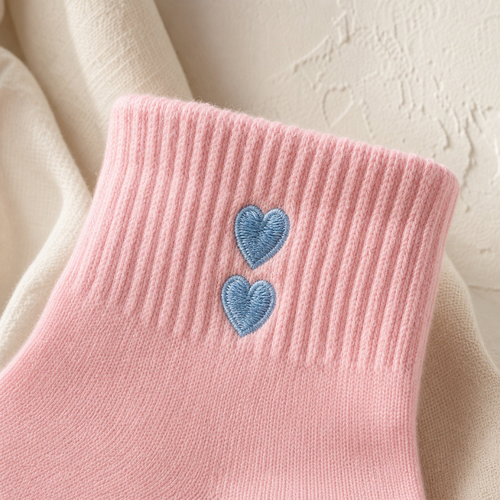Two embroidered hearts on a blush studio sock cuff