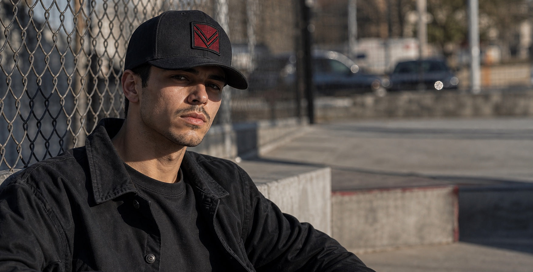 Male model wearing a black Vortray patch cap beside an outdoor city court