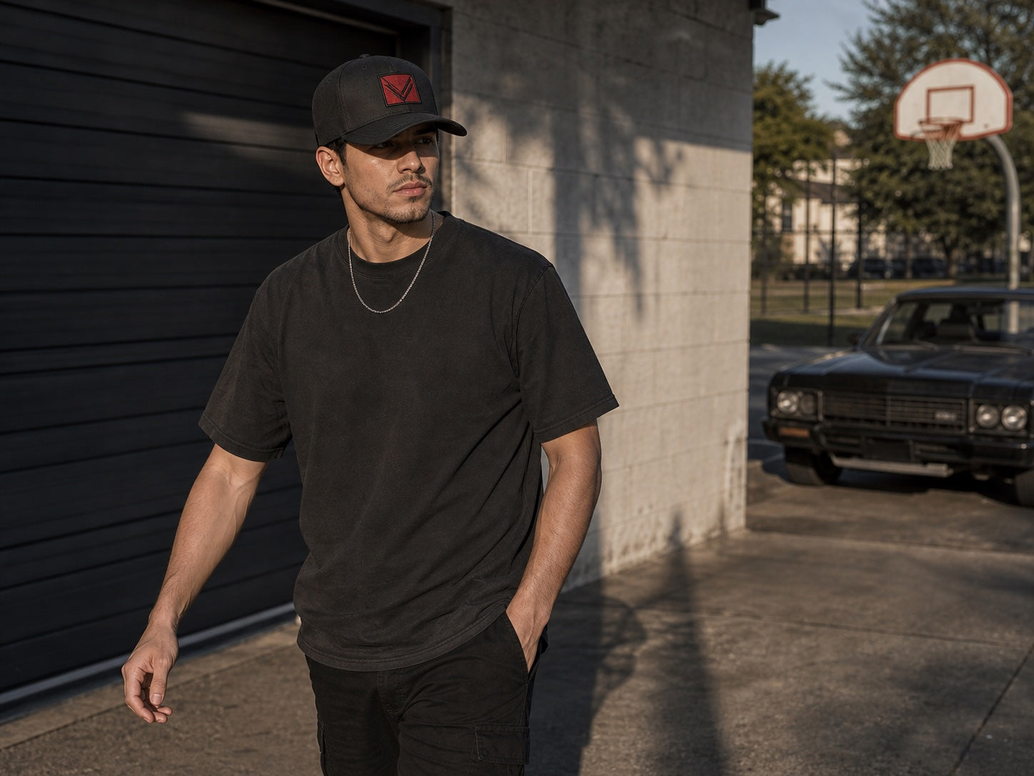 Male model wearing a black Vortray patch cap near an outdoor court