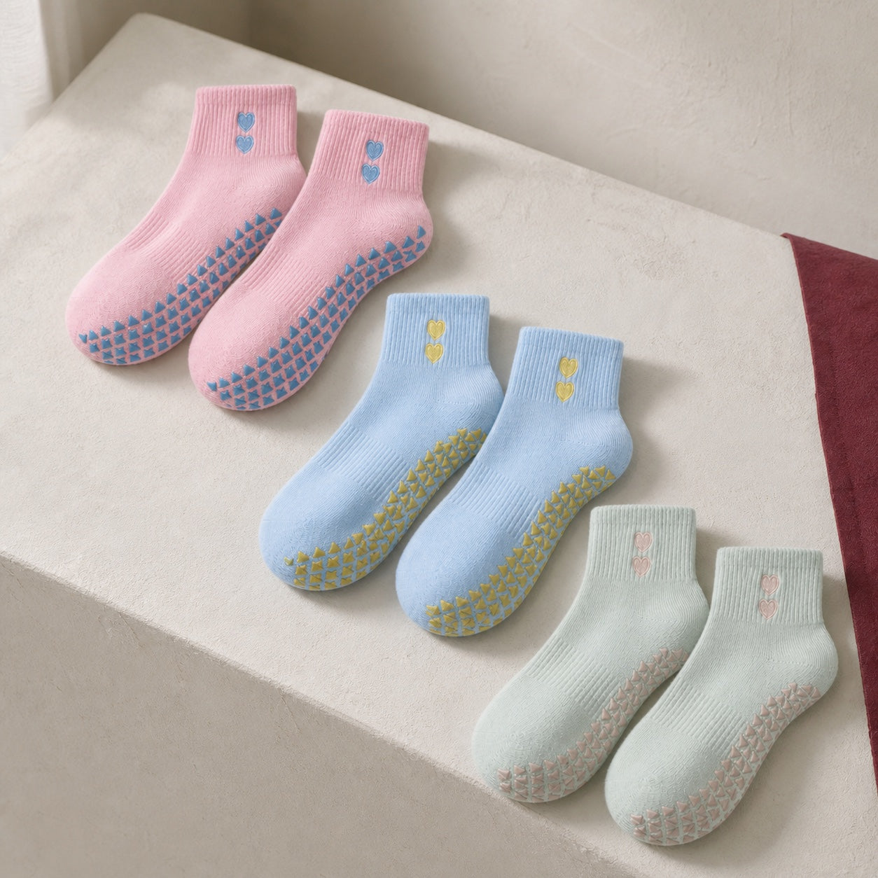 Blush, blue and sage VORTRAY grip socks on a softly lit studio bench